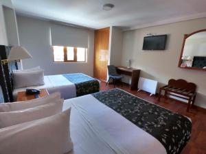 普诺Casona Plaza Hotel Puno的酒店客房配有两张床和一张书桌