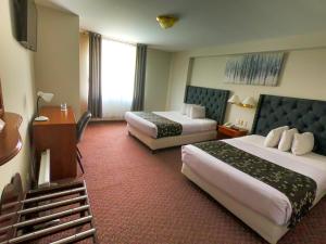 普诺Casona Plaza Hotel Puno的酒店客房设有两张床和电视。