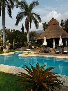 加尔潘VILLAS EL ENCANTO的一座带游泳池和茅草建筑的度假村