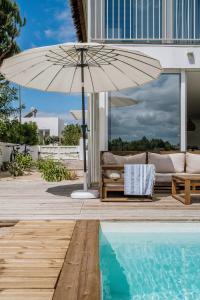 孔波尔塔Villa Possanco, Comporta beach villa的一个带沙发和遮阳伞的庭院,毗邻一个游泳池