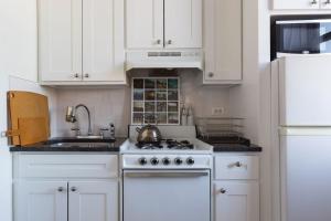 纽约Sunny Stylish West Village Condo的厨房配有白色橱柜和炉灶上的茶壶