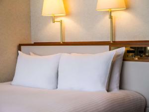串本町Mercure Wakayama Kushimoto Resort & Spa的一张带白色枕头的床和两盏灯