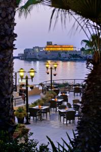 圣朱利安斯马耳他科林西亚海滩海滨度假酒店的水边餐厅,配有桌椅
