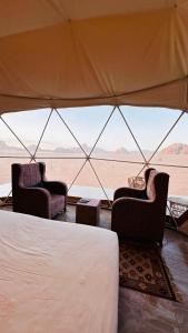瓦迪拉姆wadi rum fox road camp & jeep tour的帐篷配有两把椅子,享有沙漠美景