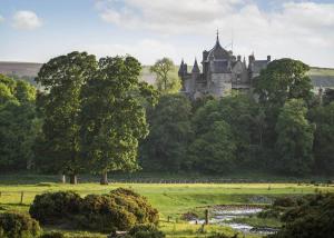 LauderThirlestane Woodland Lodges的一座城堡,位于郁郁葱葱的绿色田野上