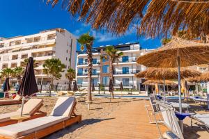 都拉斯Sea View Apartments ELDO的一个带椅子和遮阳伞的海滩和一家酒店
