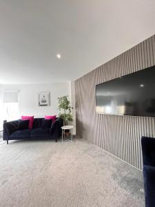 格拉斯哥Glas-Go 2 bedroom Apartment 3 min walk to SECC Hydro FREE PARKING ONSITE的客厅配有黑色沙发和粉红色枕头。