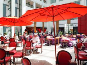 达曼达曼商业园诺富特酒店的一间设有红伞的餐厅,还有坐在桌子上的人