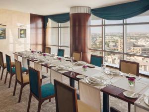 布赖代卡西姆瑞享酒店的长长的用餐室配有长桌子和椅子