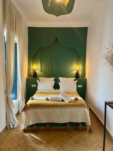 马拉喀什Riad Dar Marrakcha的一间卧室设有一张大床和绿色的墙壁