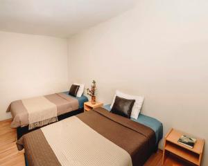 库斯科库奥斯乔瓦斯酒店的小房间设有两张床和一张桌子