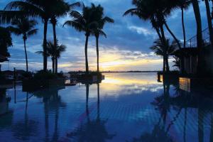 科钦科钦泰姬陵马拉巴尔度假酒店的日落时分棕榈树和海洋的游泳池