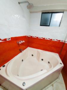 利马hostal paris的浴室配有白色浴缸,浴室设有红色墙壁