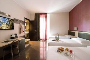 米兰费弗酒店的酒店客房设有两张床和一张带食物盘的桌子。