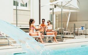 里米尼Hotel Regina Elena 57 & Oro Bianco SPA的一群人坐在游泳池边