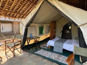 安博塞利Amboseli Discovery Camp的帐篷内的卧室,配有一张床和一张桌子