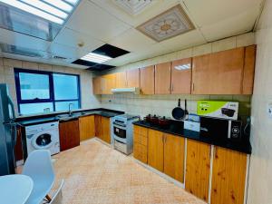 阿吉曼Modern Living Fully Equipped Room For Rent的厨房配有木制橱柜、洗衣机和烘干机