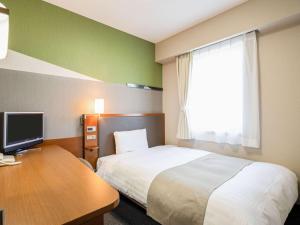 富山舒适酒店富山的酒店客房配有一张床、一张书桌和一台电视。