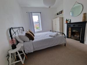 惠特利湾Lovely 3 bedroom Whitley Bay Townhouse.的一间卧室配有一张带壁炉和镜子的床
