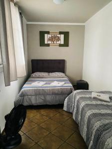 瓜鲁柳斯HOSTEL ANPRADO的一间卧室配有两张床和椅子