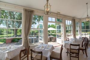 林德赫斯特巴特利旅舍酒店的一间设有白色桌椅和窗户的用餐室