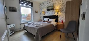 斯哈亨Bed & Breakfast Moments的一间卧室配有一张带椅子的床和一扇窗户