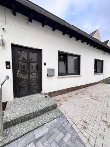 Ferienhaus in Wilsenroth的白色的房子,设有黑色的门和庭院