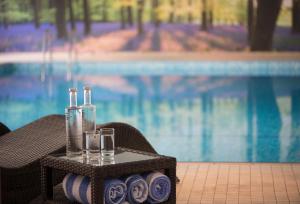 林德赫斯特森林酒店的一个带两瓶和眼镜的托盘,放在一个游泳池旁的桌子上