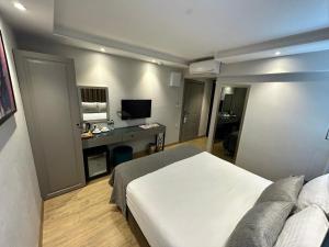 伊斯坦布尔The Roomy Hotel Nişantaşı的一间卧室配有一张床和一张书桌及电视