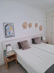 蒙蒂戈杜Apartamentos Dom Henrique的一间卧室设有两张床和两张带台灯的桌子。