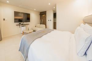 西归浦市Haeilri Pool&SPA Hotel的卧室配有白色的床和电视
