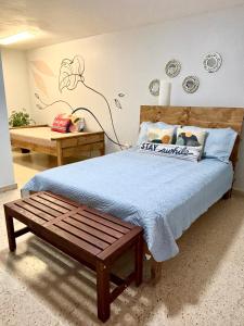 圣胡安Bee Inn Puerto Rico Charming Urban Apartment in San Juan的一间卧室配有一张带蓝色毯子和长凳的床