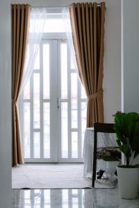 芹苴Miha Villa Can Tho的带有窗帘和盆栽的大玻璃门