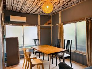 汤河原町温泉街の入り口にあるゲストハウス SLOW HOUSE yugawara的一间带木桌和椅子的用餐室