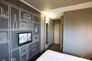 Yffiniac宜必思圣布里克菲尼亚克酒店的一间卧室设有黑色墙壁,配有电视