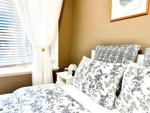 兰利Langley 半地下室独立出入温馨卧房-桐花草堂的卧室配有带枕头的床铺和窗户。