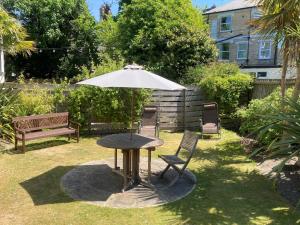 伯恩茅斯Cavendish Central Bournemouth的一张桌子、一把伞、两把椅子和一张长凳