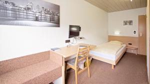 莱茵河畔威尔维多利亚酒店的小房间设有一张桌子和一张床