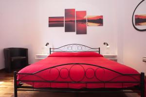 卡利亚里Visit Cagliari的卧室内的一张红色的床,墙上挂着绘画作品