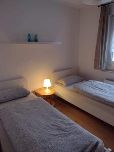 NauortFerienwohnung mit Herz的一间卧室设有两张床和一张桌子上的台灯。