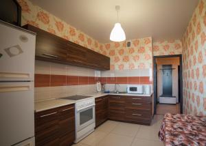 沃罗涅什ATLANT Apartments 219的厨房配有木制橱柜和白色炉灶烤箱。