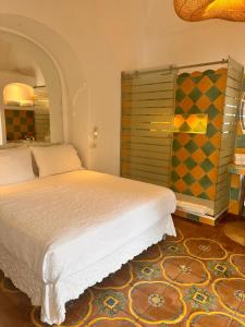 波西塔诺玛利亚别墅套房旅馆的卧室配有白色的床和色彩缤纷的墙壁