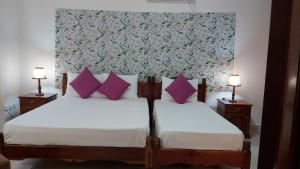 Au CapEmma's Guest House and Self-Catering的一间卧室配有两张带紫色枕头的床