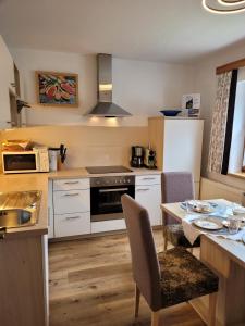 迈尔霍芬Ferienwohnung Zuppinger的厨房配有白色橱柜和桌椅