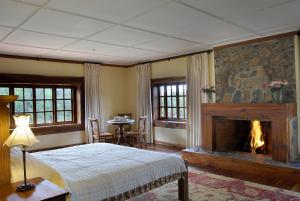 纳纽基Mukima Manor的一间卧室设有壁炉、一张床和一张桌子