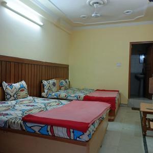 德拉敦Hotel Rajpal Guest House的一间卧室配有两张床和电视。