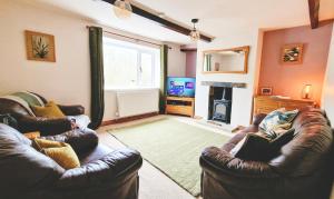 霍姆弗斯THE OLD WASH KITCHEN - Charming Character Cottage in Holmfirth, Yorkshire的客厅配有两张真皮沙发和一台电视机