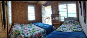 莱瓦镇Casa de leña, cabaña rural的一间卧室设有两张床和两个窗户。