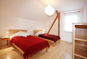 马尔欣Naturerlebnis的一间卧室配有两张带红色床单和灯的床