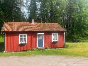 BottnarydSjönära stuga Bottnaryd的红色的房子,有两个窗户和蓝色的门